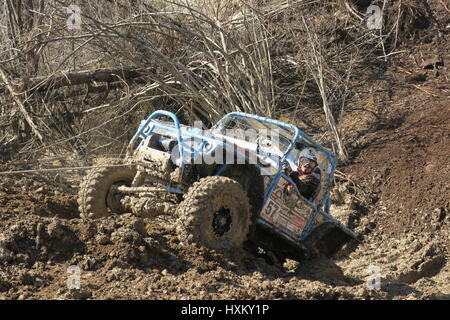 A off-road car is pulled uphill with steel wire by hydraulics of an excavator. A close-up photo. From a muddy trench uphill on a very mud ground Stock Photo