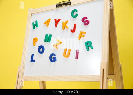 Colourful letter magnets being positioned on whiteboard Stock Photo