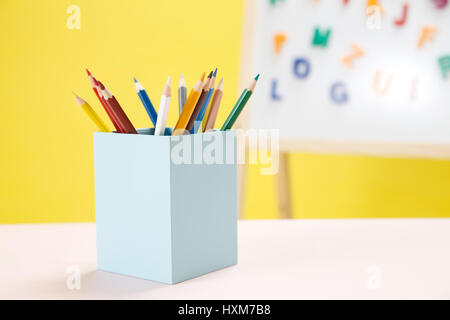 Colourful letter magnets on whiteboard and colourful pencils Stock Photo