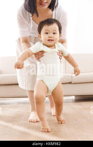Mother helping baby boy learn to walk Stock Photo