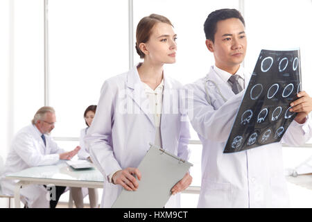 Doctors examining x-ray report in hospital. Stock Photo