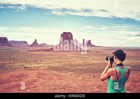 Vintage toned picture of female fit photographer takes pictures of buttes in the Monument Valley, USA.