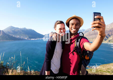 Portrait of loving young couple on holiday taking selfie with smart phone Stock Photo