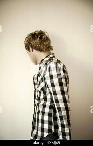 Man in Checked Shirt Against Interior Wall Stock Photo