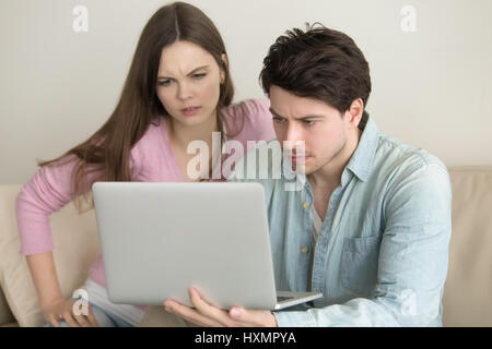 Young couple using laptop computer, having problems, anxious and Stock Photo