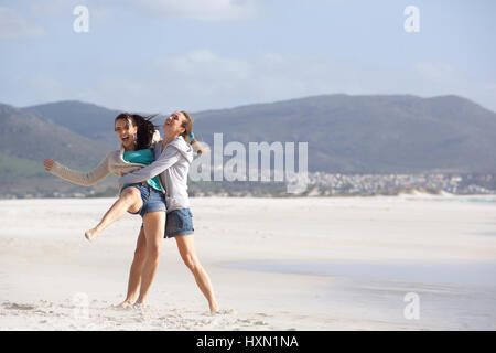 Portrait of two playful girlfriends having a good time at the beach Stock Photo