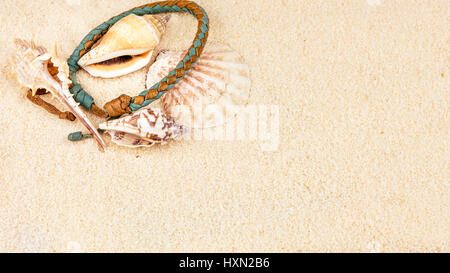Sea shells and coloured wristbandon on sandy beach Stock Photo