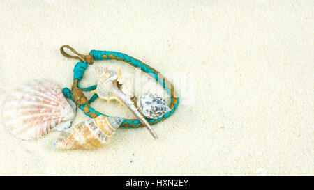 Sea shells and coloured wristbandon on sandy beach Stock Photo