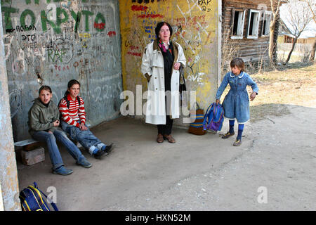 Tver, Russia - May 2, 2006: Rural schoolgirls and their teacher, expect transport at the bus stop Stock Photo