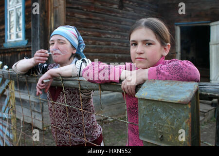 Lipovec village, Tver region, Russia - May 1, 2006: Tanya Girl 11 years old, standing at the fence of rural house near her mother smokes. Stock Photo