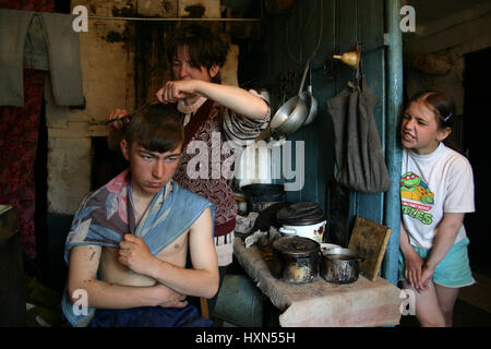 Lipovec village, Tver region, Russia - May 7, 2006: Family Russian farmers in his home, Mother makes her son hairstyle, rural house. Stock Photo