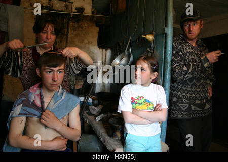 Lipovec village, Tver region, Russia - May 7, 2006: Family Russian peasants in his home, Mother cuts the hair son indoors kitchen, in the presence of  Stock Photo