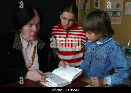 Podol village, Tver region, Russia - May 2, 2006:  Rural teacher reads textbook girls schoolgirls in the classroom primary school. Stock Photo