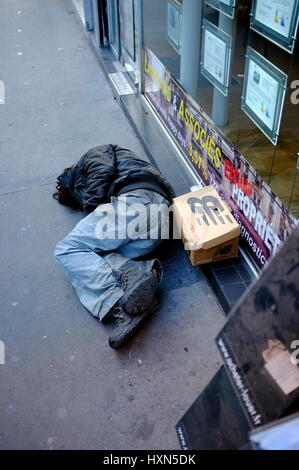 AJAXNETPHOTO. PARIS, FRANCE. - DOWN AND OUT - UNIDENTIFIED INDIVIDUAL IN DISHEVELLED CLOTHING AND DAMAGED FOOTWEAR SLEEPING ROUGH ON A CITY PAVEMENT.  PHOTO:JONATHAN EASTLAND/AJAX REF:FX112703 5273 Stock Photo