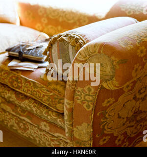 Cushion on floral patterned sofa. Stock Photo