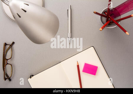 High angle view of a collection of desk elements such as pencils, notebook, lamp, eyeglasses, pen and eraser in a modern style Stock Photo