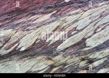 Close up of colorful rock surface, natural background, pattern and texture. Metamorphic white quartzite folded and fractured together with red coarse  Stock Photo