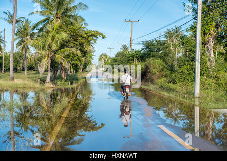 Motorbiker driving south of Hua Hin after heavy rain. The wet season in Thailand was delayed in 2016 with heavy rains continuing into January 2017. Stock Photo