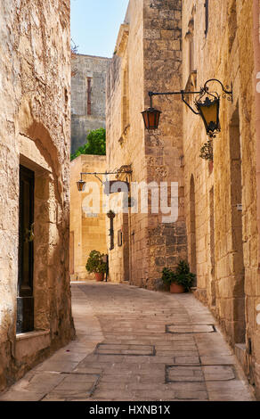 Mdina, MALTA - JULY 29, 2015: The narrow medieval stone paved street with the restaurant “Medina” in the Mdina, the old capital of Malta. Stock Photo