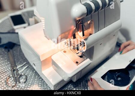 White modern overlock machine, woman hitting a piece of cloth on a small table. Stock Photo