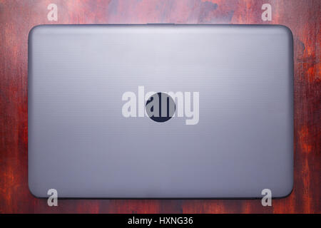 Closed laptop lying on a wooden surface mahogany. Stock Photo