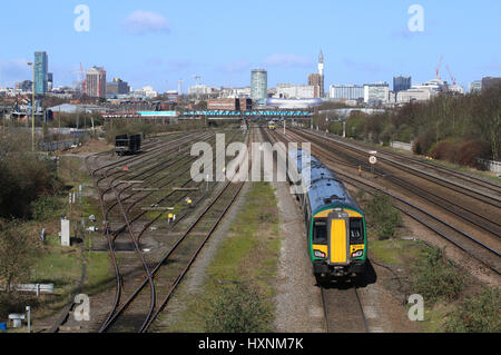 Passenger train services heading into and out of Birmingham city centre, West Midlands, England, UK and a view of the city centre skyline. Stock Photo