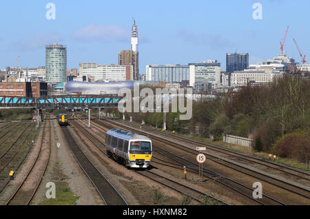 Passenger train services heading into and out of Birmingham city centre, West Midlands, England, UK and a view of the city centre skyline. Stock Photo