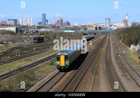 Passenger train services heading into and out of Birmingham city centre, West Midlands, England, UK and a view of the city centre skyline. Stock Photo