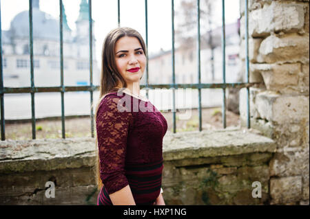 Close up portrait of young chubby teenage girl wear on red dress posed against iron fence. Stock Photo