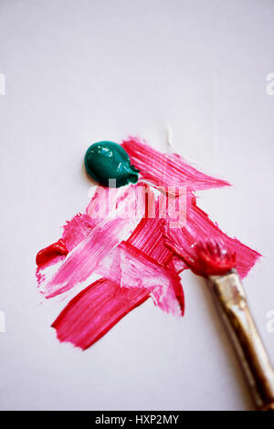 Oiled red, green and white. On a white sheet. In the corner is the brush in the paint ,Plenty of space, minimalism Stock Photo