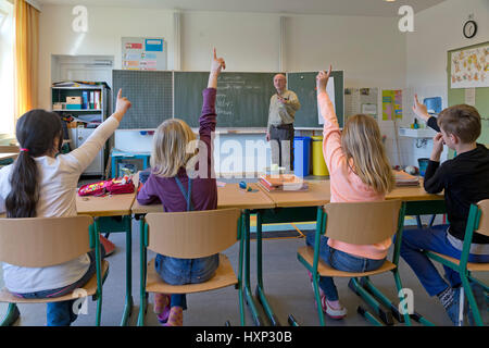 children raising their hands at primary school Stock Photo