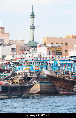 Old, wooden vessels moored at Dubai Creek with the Old Souq and the Gold Souq Mosque in the background. Stock Photo