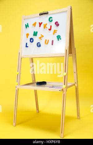 Colourful letter magnets being positioned on whiteboard Stock Photo