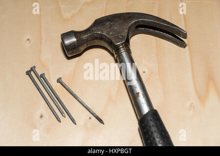 Closeup of a hammer and nails at a wooden surface Stock Photo