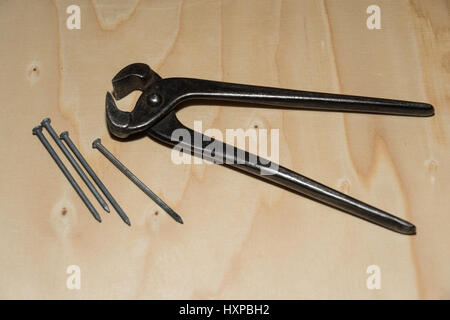 Pincer and nails closeup on a wooden surface Stock Photo