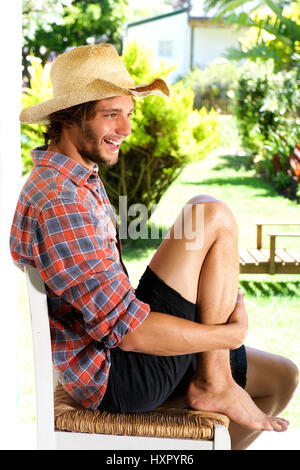 Full body portrait of smiling young man wearing cowboy hat outside Stock Photo