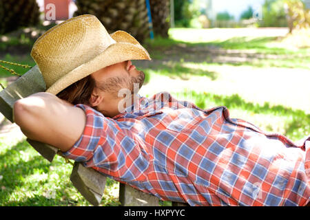 Side portrait of young man lying on hammock resting with cowboy hat Stock Photo