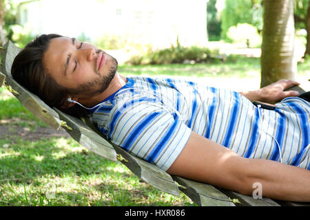 Portrait of attractive young man relaxing on hammock with headphones Stock Photo