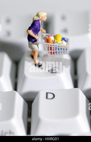 Woman by shopping cart on computer keyboard, on-line shopping, Frau mit Einkaufswagen auf Computertastatur, Online-Shopping Stock Photo