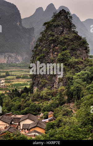 Yangshuo, Guangxi, China - March 29, 2010: Aerial view of the karst hills around Guilin and the tiled roofs of stone farmhouses in a peasant village.  Stock Photo