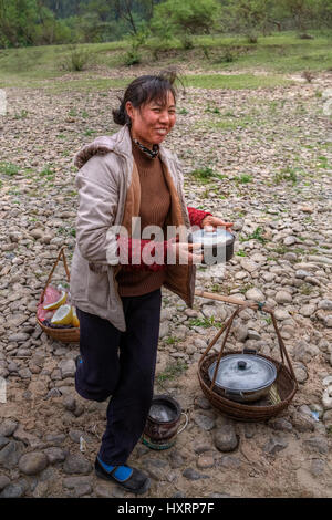 Yang Di village, Yangshuo, Guangxi, China - March 29, 2010: Asian woman street vendor hot food holding a pot of food and smiling countryside in southe Stock Photo