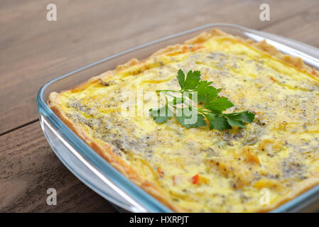 Quiche lorraine in square baking form on wooden background Stock Photo