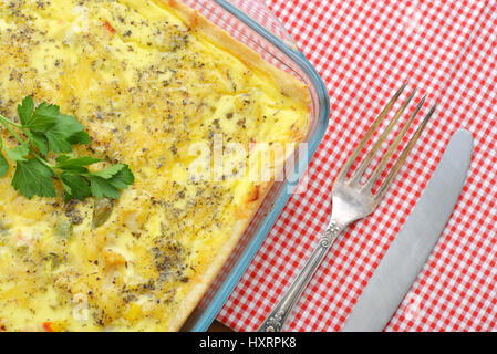 Quiche lorraine in square baking form on wooden background Stock Photo