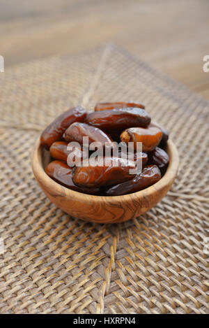 Dates fruit in a wooden bowl closeup on wooden background Stock Photo