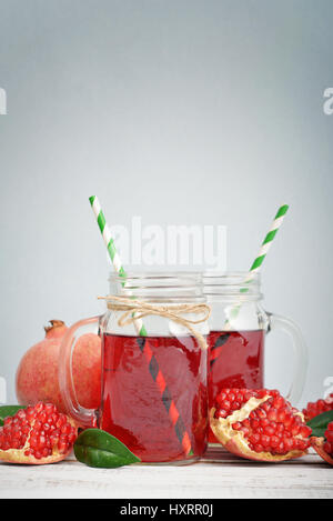 Pomegranate juice in jar with handle and fresh fruits  on blue background Stock Photo