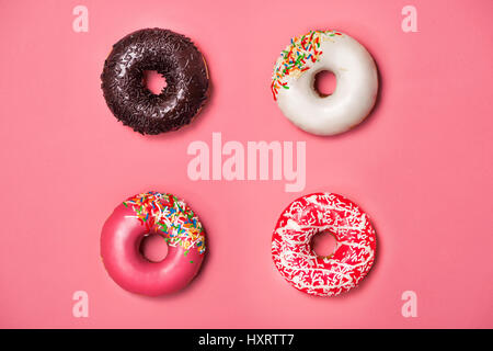 Donuts with icing on pastel pink background. Sweet donuts. Stock Photo