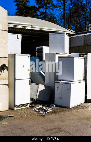 Discarded fridges and freezers at a local waste station. Here they stand in wait for transport to be recycled. Logos removed. Stock Photo