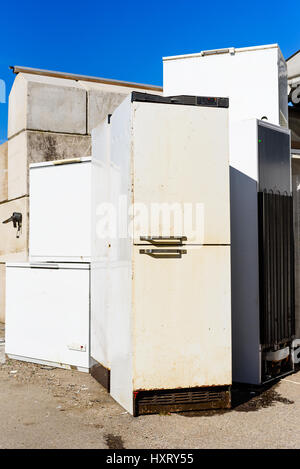 Discarded fridges and freezers at a local waste station. Here they stand in wait for transport to be recycled. Logos removed. Stock Photo