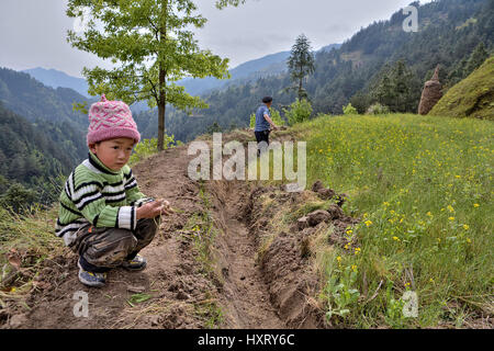 Langde Village, Guizhou, China - April 15, 2010: Rural China, mountainous terrain, unidentified boy about 4 years old is sitting near a farmer's field Stock Photo