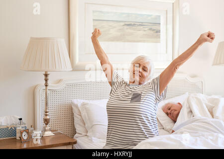 Senior woman waking up with a stretch in the morning  Stock Photo